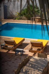 a swimming pool with two picnic tables next to it at Riad Dar Sarah in Taghazout