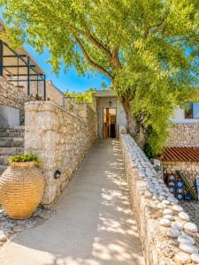 a stone wall with a tree and a walkway at Lalloudes Hotel Mani in Éxo Nímfion