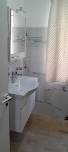 a white bathroom with a sink and a mirror at Villa K & N in Sarandë +10 photos