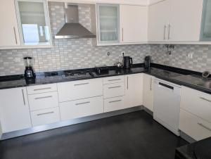a kitchen with white cabinets and black counter tops at Loreto Luxury in Arco da Calheta