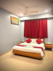 a bedroom with a bed with a red curtain at Hotel Happinex Inn in Surat