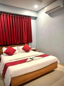 a bedroom with a large bed with red curtains at Hotel Happinex Inn in Surat +9 photos