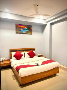 a bedroom with a large bed with red pillows at Hotel Happinex Inn in Surat