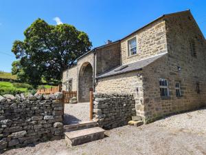 an old stone building with a stone wall at Ragged Hall Barn in Settle
