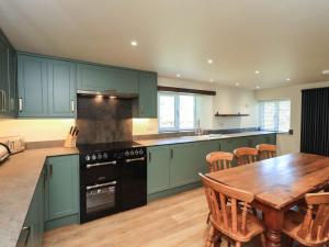 a kitchen with green cabinets and a wooden table at Ragged Hall Barn in Settle