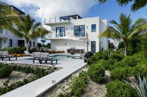 a white house with a swimming pool and palm trees at Pestica Villa Private Pool in Leeward