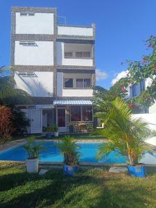a building with a swimming pool in front of it at First floor apartment with view and balcony and with charming pool near sandy beach and commerces in Pointe aux Biches