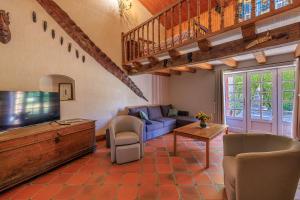 a living room with a blue couch and a tv at L'Etable de Sauvignac - Avec piscine privée in Sauvignac