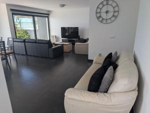 a living room with a white couch and a clock at Loreto Luxury in Arco da Calheta