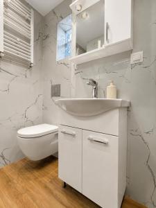 a white bathroom with a sink and a toilet at AZEK Garden Suite in Perea