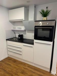 a white kitchen with a sink and a microwave at Gemütliche City Wohnung in Mönchengladbach