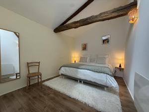 a white bedroom with a bed and a chair at Etxean irria in Hasparren