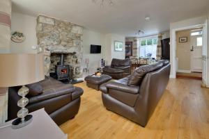 a living room with leather furniture and a stone fireplace at Finest Retreats - Artro View in Llanbedr