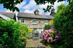 a stone house with a table and chairs and flowers at Finest Retreats - Artro View in Llanbedr