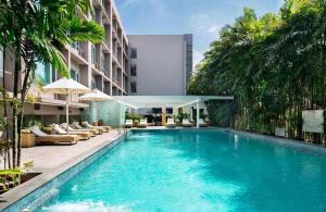 a swimming pool in front of a building with palm trees at Radisson Blu Bengaluru Outer Ring Road in Bangalore