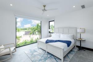 a white bedroom with a bed and a large window at Pestica Villa Private Pool in Leeward +36 photos