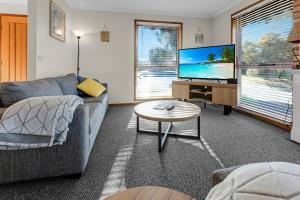 a living room with a couch and a tv and a table at Paradise on Sheerwater in Paynesville