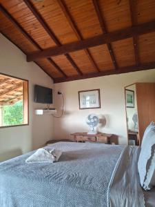 a bedroom with a large bed with a wooden ceiling at Pouso Canarinho in Carrancas +4 photos
