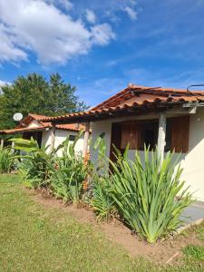 a white house with a red roof and some plants at Pouso Canarinho in Carrancas