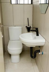 a bathroom with a toilet and a sink at Ultimate Lotus in Manzini