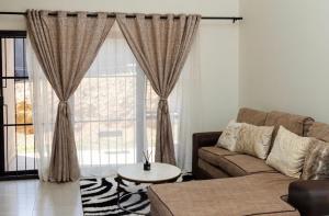 a living room with a couch and a large window at Ultimate Lotus in Manzini