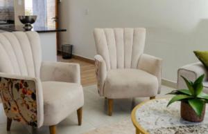 a living room with two chairs and a table at Ultimate Lotus in Manzini +1 photo