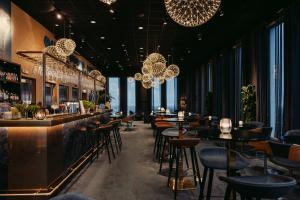 a bar with tables and chairs and chandeliers at Best Western Malmo Arena Hotel in Malmö