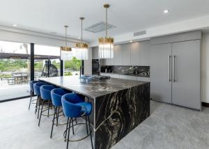 a kitchen with a large marble counter and blue bar stools at Pestica Villa Private Pool in Leeward