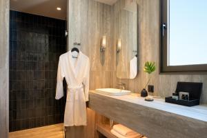 a bathroom with a sink and a robe on a counter at Mitsis N'U Piraeus Port in Piraeus +44 photos