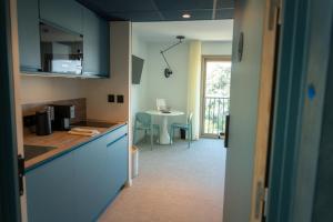 a kitchen with blue cabinets and a table at Apparté Plus in Brive-la-Gaillarde +40 photos