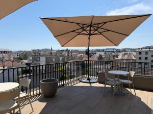 a patio with an umbrella and tables and chairs on a balcony at Apparté Plus in Brive-la-Gaillarde