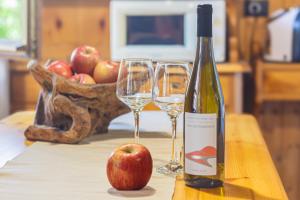 a bottle of wine and an apple on a table at Betù Holiday Apartment in Castello di Fiemme