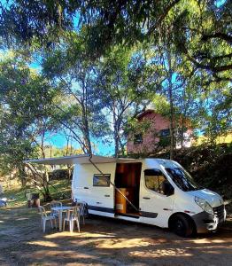 a white van parked under a tree with a table at Van Home in Lavrinhas