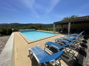 a row of lounge chairs next to a swimming pool at Villa Vallon Pont d'Arc in Vallon-Pont-dʼArc