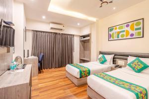 a hotel room with two beds and a television at Treebo Premium Widlor Boutique with Swimming Pool in Mumbai +42 photos