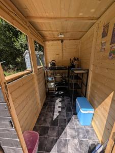 an inside view of a wooden cabin with a desk at Budget stay, in lovely private setting with rustic charm, log burner, fire pit, campers kitchen & Eco Loo NO BEDDING SUPPLIED in Narberth +16 photos