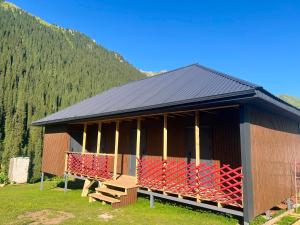 a building with red chairs in front of a mountain at Forest Yurt House Altyn Arashan in Mineralʼnyy Istochnik Altyn-Arasan +14 photos