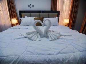 a bed with two swans made out of towels at Two Tees Apartment in Magboro-Akeran