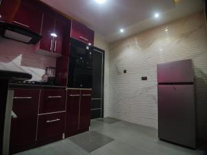 a kitchen with red cabinets and a refrigerator at Two Tees Apartment in Magboro-Akeran