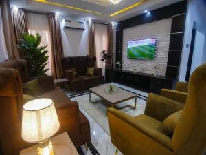 a living room with couches and a flat screen tv at Two Tees Apartment in Magboro-Akeran