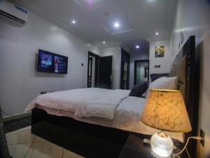 a bedroom with a large bed and a lamp at Two Tees Apartment in Magboro-Akeran