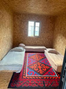a small room with two beds and a rug at Forest Yurt House Altyn Arashan in Mineralʼnyy Istochnik Altyn-Arasan