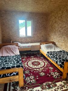 two beds in a room with a rug and a window at Forest Yurt House Altyn Arashan in Mineralʼnyy Istochnik Altyn-Arasan