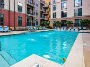 a large swimming pool with lounge chairs and buildings at Luxe Nest King Studio Downtown 2B3 in Birmingham