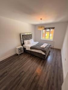 a bedroom with a bed and wooden floors and a chandelier at 3 Bedroom Central Apartment in Goodmayes