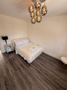 a bedroom with a bed and a chandelier at 3 Bedroom Central Apartment in Goodmayes +18 photos