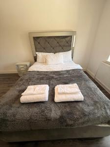 a bedroom with a bed with two towels on it at 3 Bedroom Central Apartment in Goodmayes