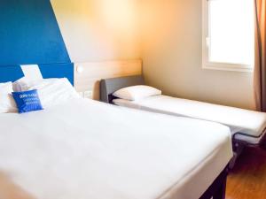 a small room with two beds and a window at ibis Budget Millau Viaduc in Millau