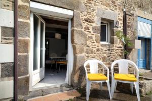 two white chairs sitting outside of a stone house at Chambre de garel in Le Minihic-sur-Rance
