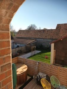 an outdoor deck with a hot tub and a backyard at Le BENEZE entre Beauce et Perche in Saint-Hilaire-sur-Yerre